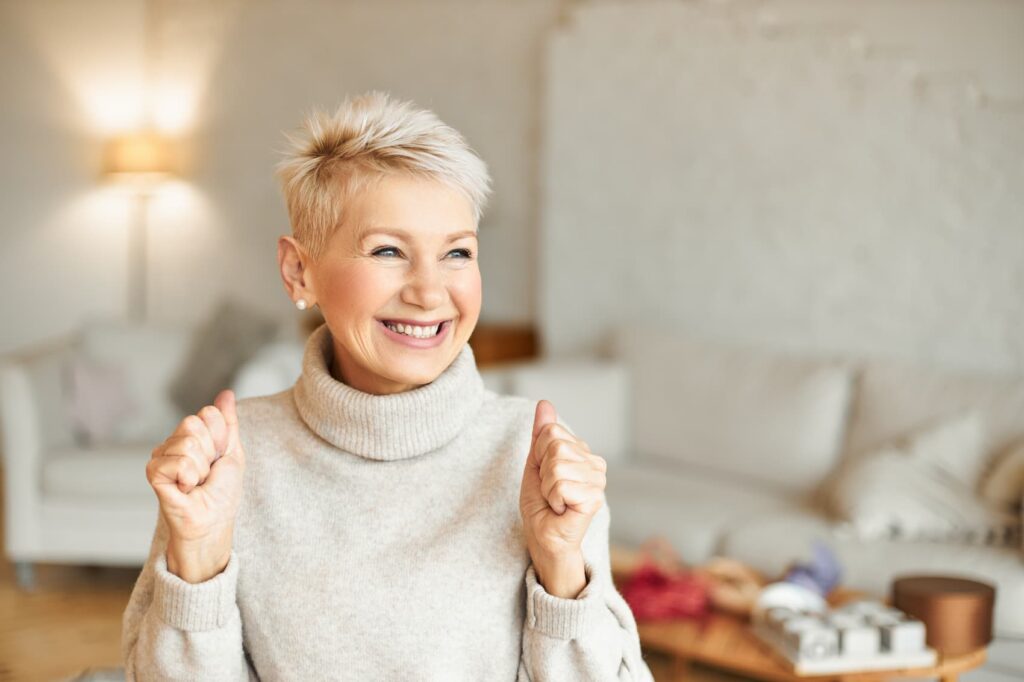 Happy mature woman celebrating indoors.