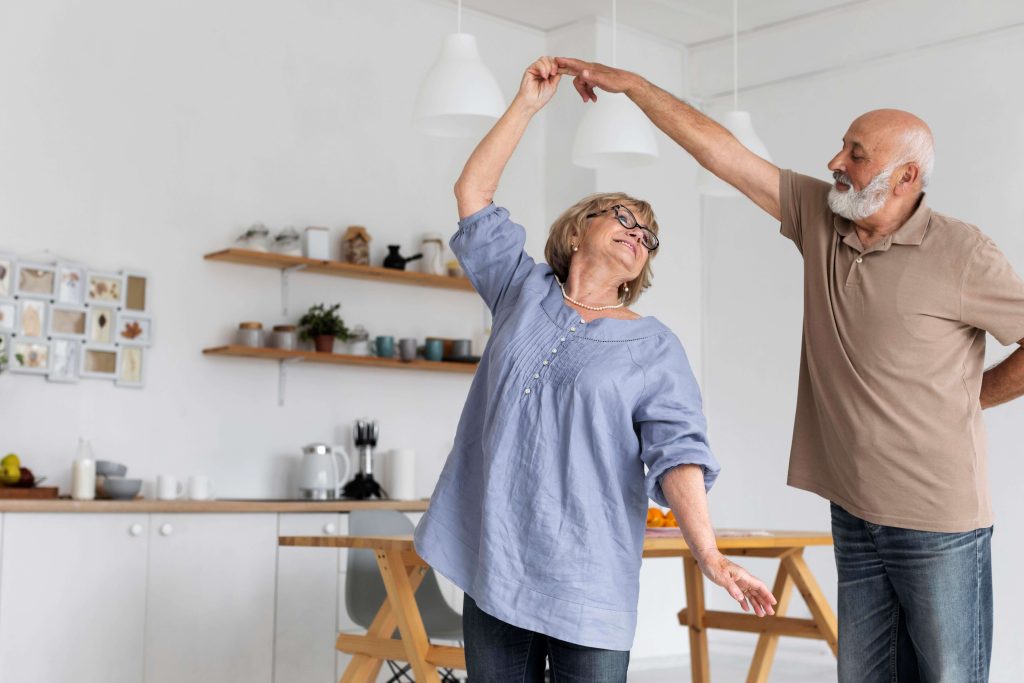 Elderly couple dancing joyfully indoors.