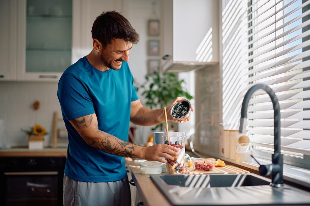 Man preparing smoothie in kitchen.