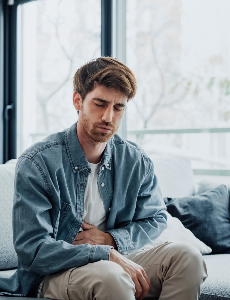 Man sitting, holding stomach in discomfort.